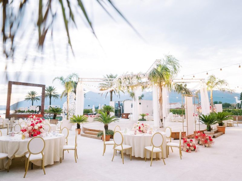festive-tables-with-colorful-bouquets-flowers-stand-around-round-stage-seashore-against_278455-45793
