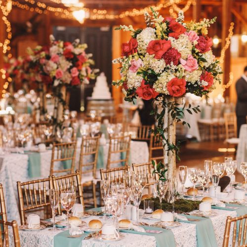 Yellow light garlands hang over the dinner tables decorated with pink bouquets